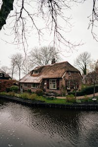 Traditional thatched roof cottage by a canal in picturesque Giethoorn, Holland.