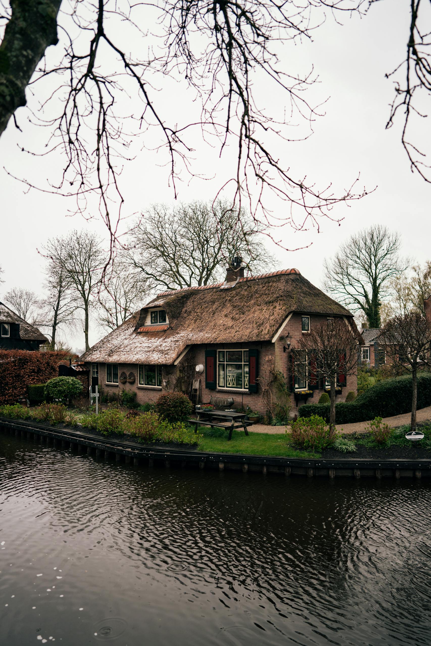 Traditional thatched roof cottage by a canal in picturesque Giethoorn, Holland.