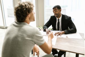 Two men having a discussion over documents in a modern office setting.